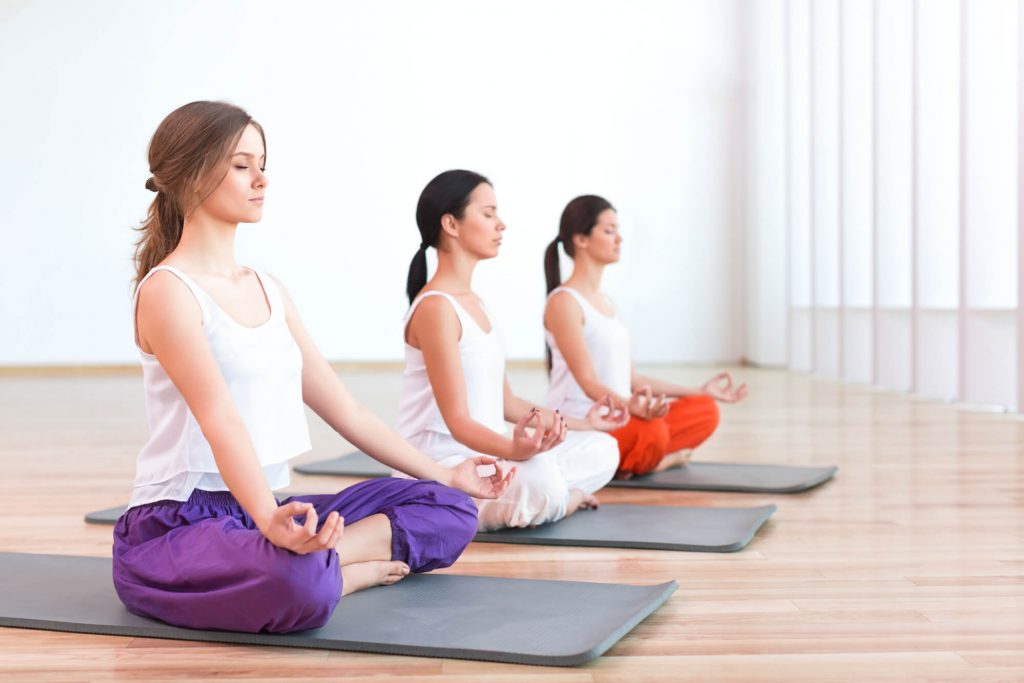 três mulheres praticando yoga